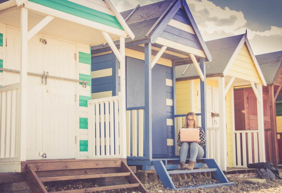 Paula sitting on beach huts with laptop.jpg